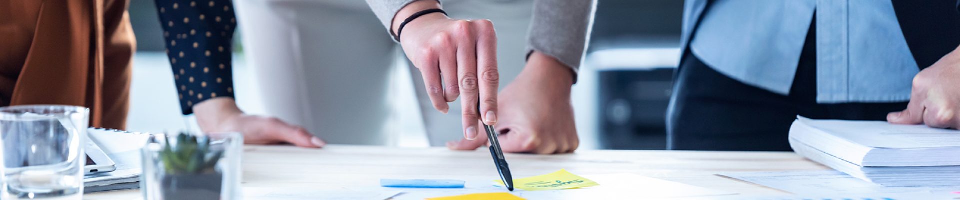 Close-up of the hands of business people pointing at the statistics of the company in the office.