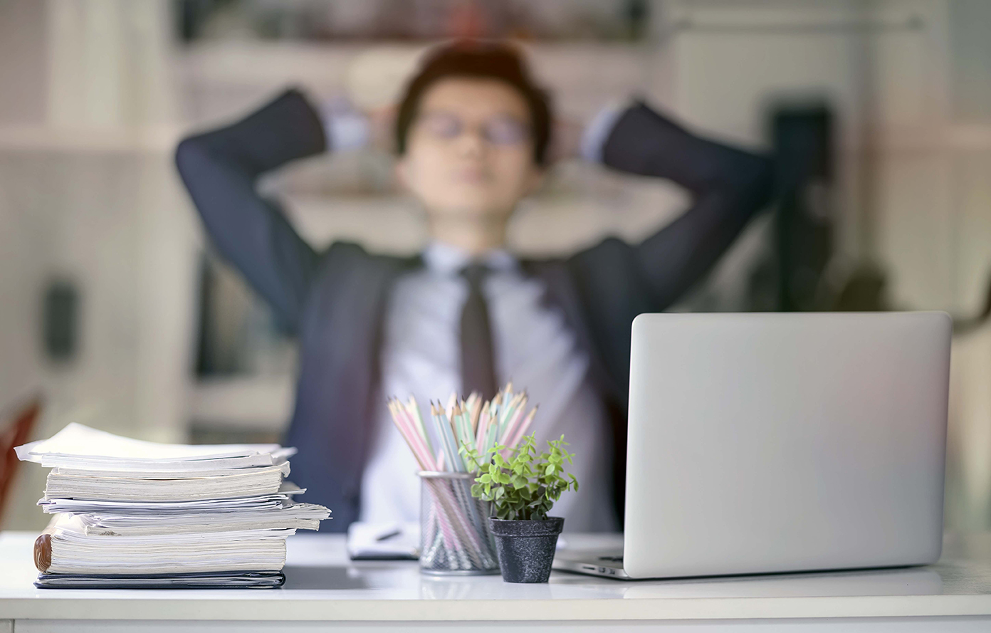 Stack of documents at workplace and blur image of male employee on background.