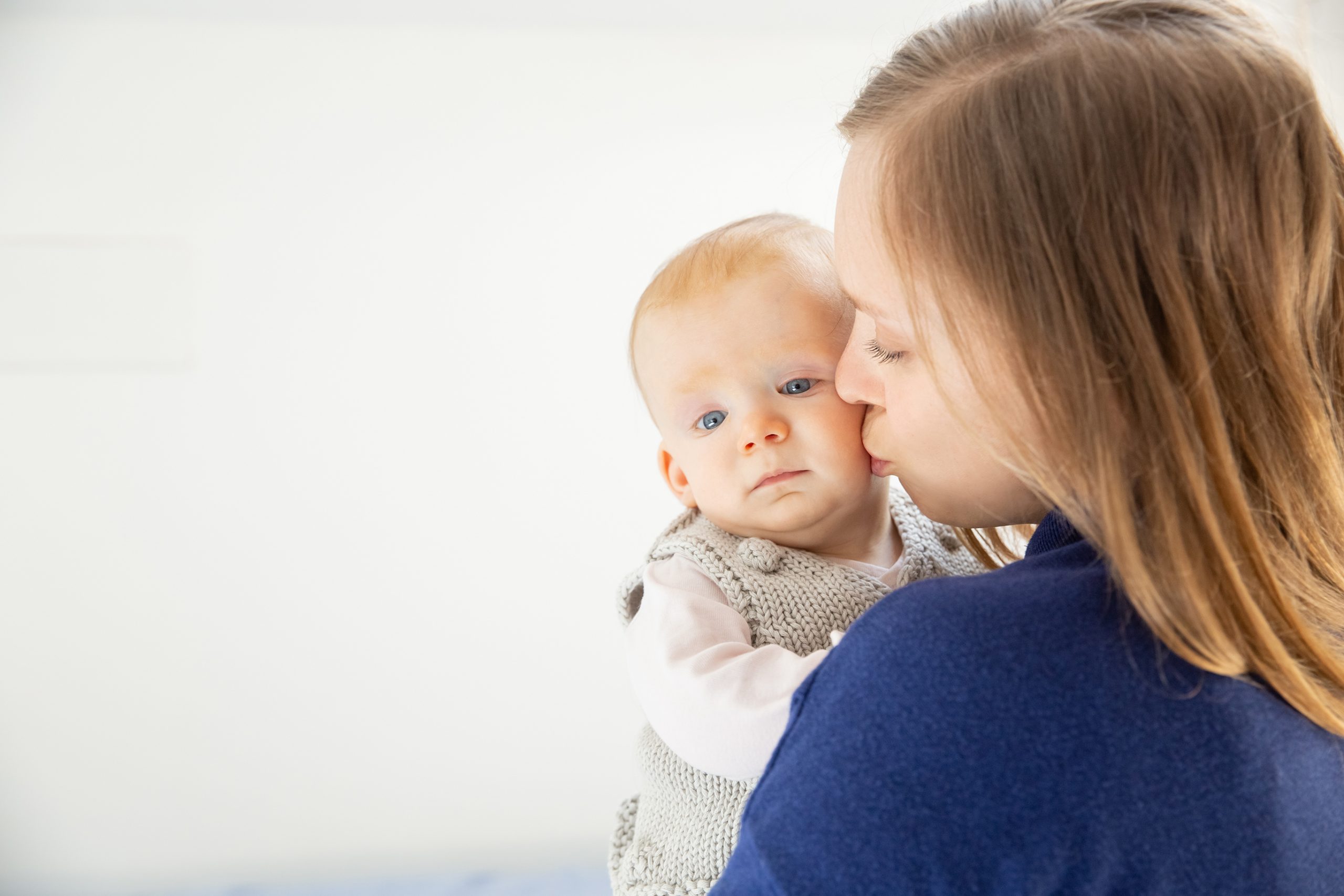 Young mother kissing cute infant child. Beautiful happy young woman hugging adorable infant baby girl. Motherhood concept