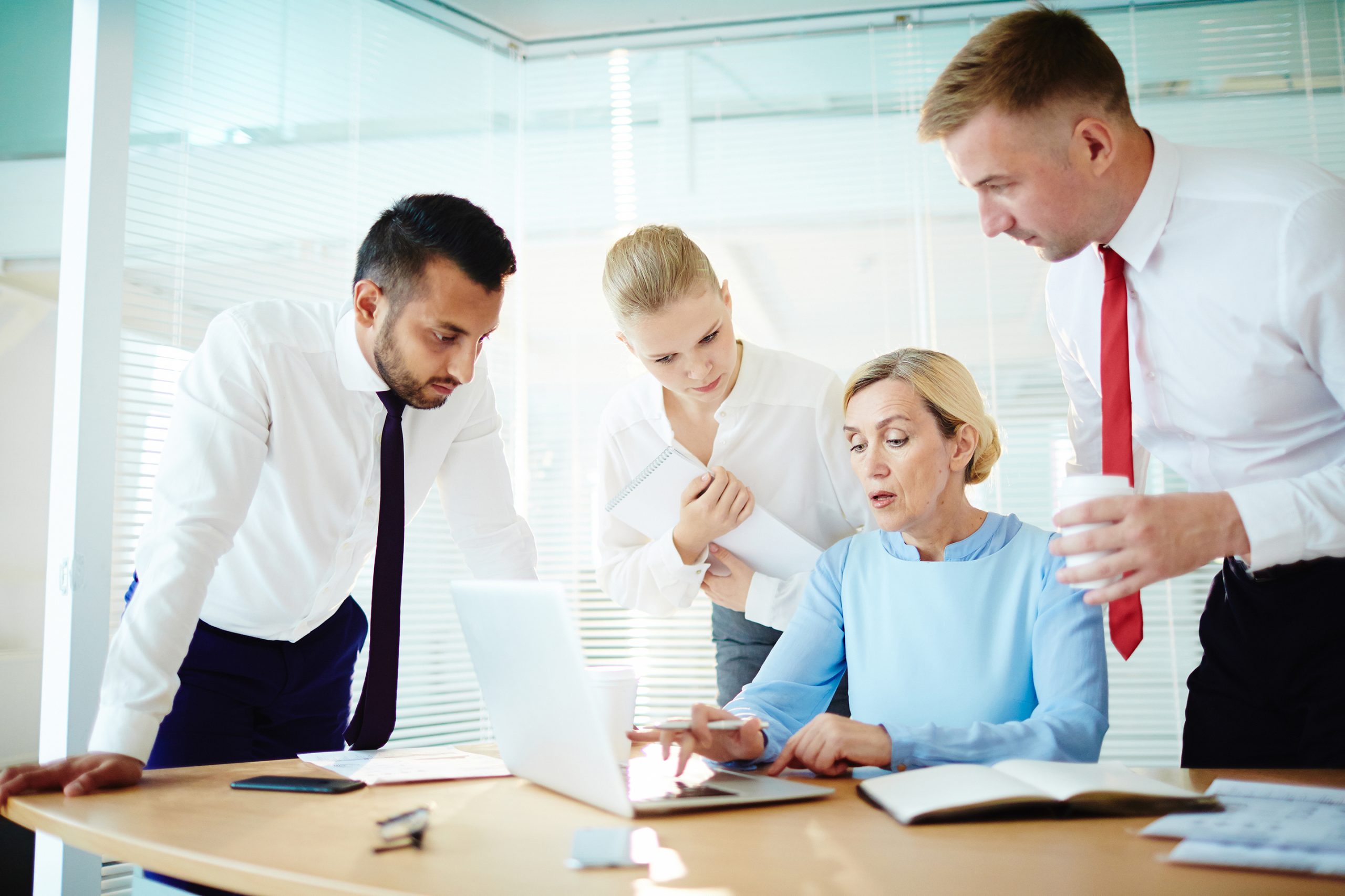 Mature employer making online presentation for her subordinates at start-up meeting in office